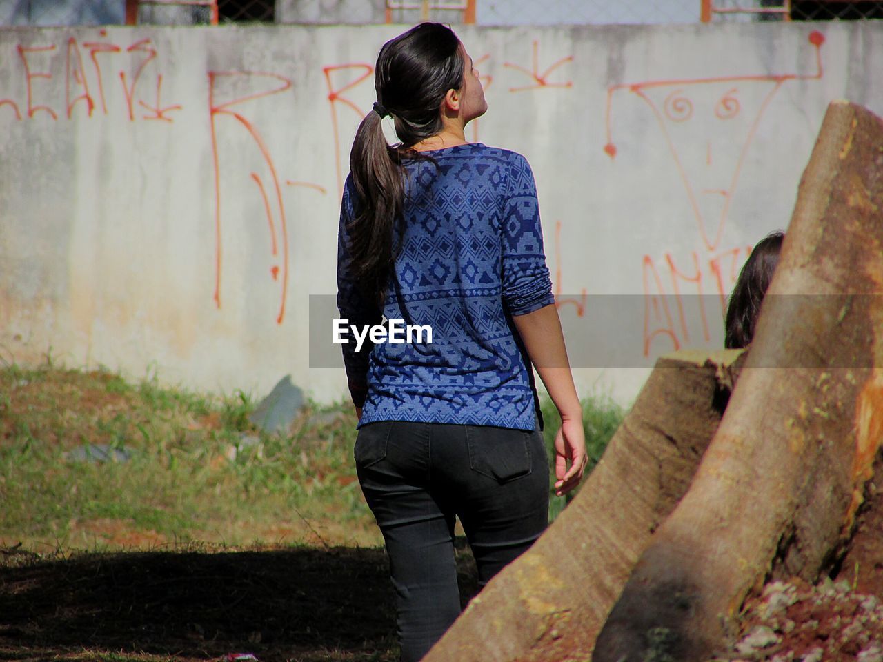 FULL LENGTH REAR VIEW OF WOMAN STANDING AGAINST WALL