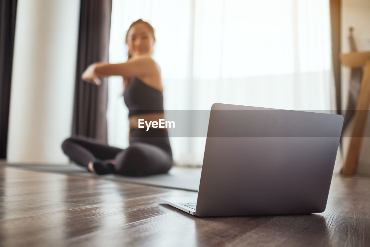 young woman using laptop while sitting on table