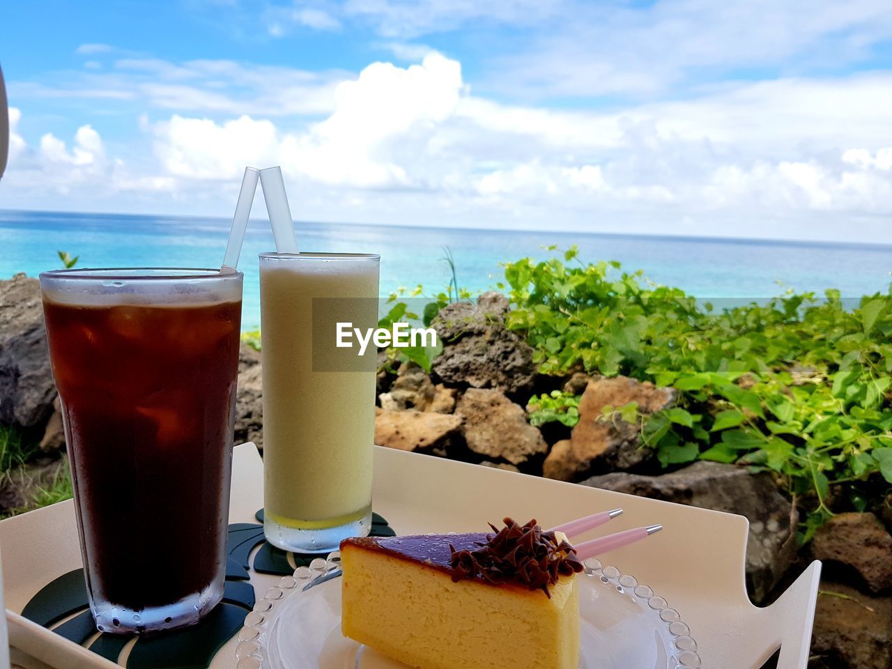 CLOSE-UP OF DRINK ON TABLE BY SEA