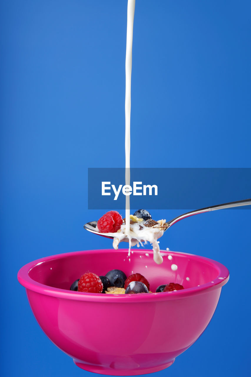 Close-up of milk on breakfast cereal against blue background