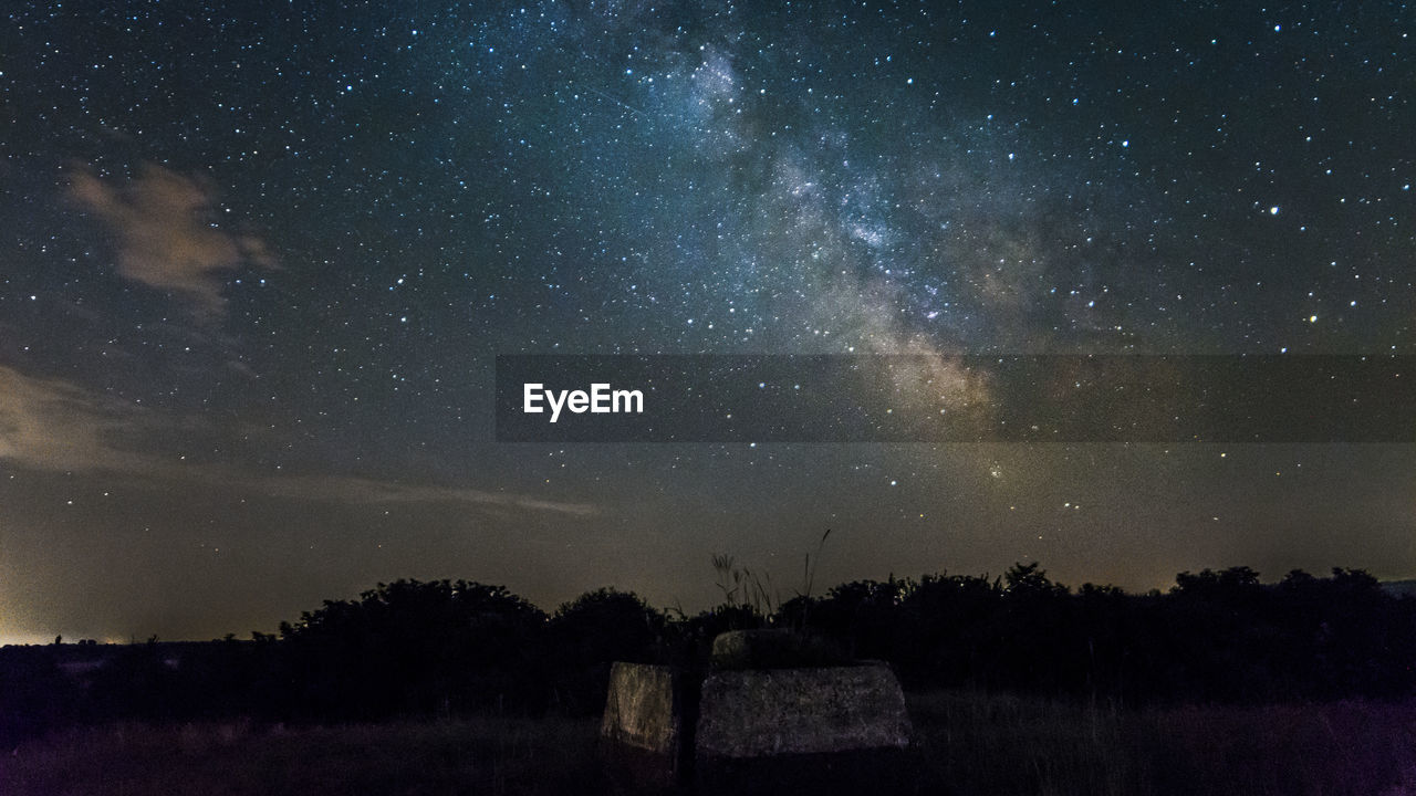 Scenic view of field against sky with star field at night