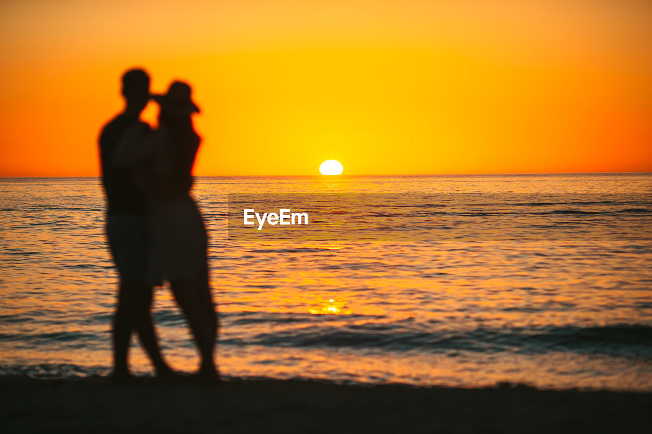 silhouette woman standing on beach against sky during sunset