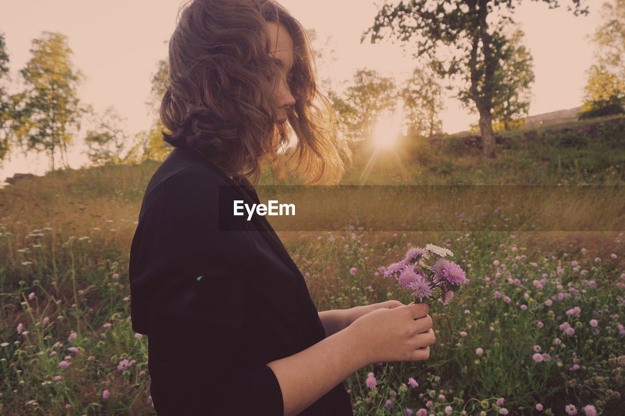 Woman holding purple flowers on field