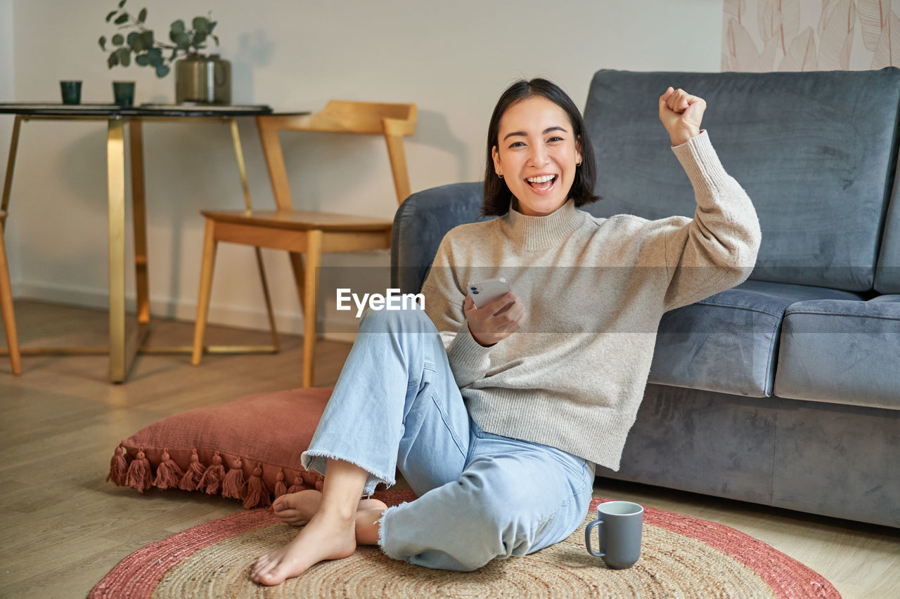 portrait of young woman sitting on sofa at home