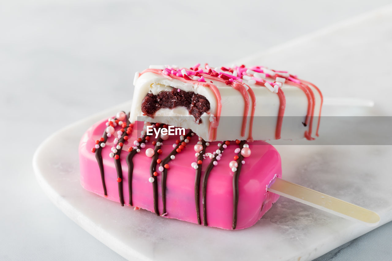 Valentine's day cakesicles on a marble slab with a bite out of the one on top.