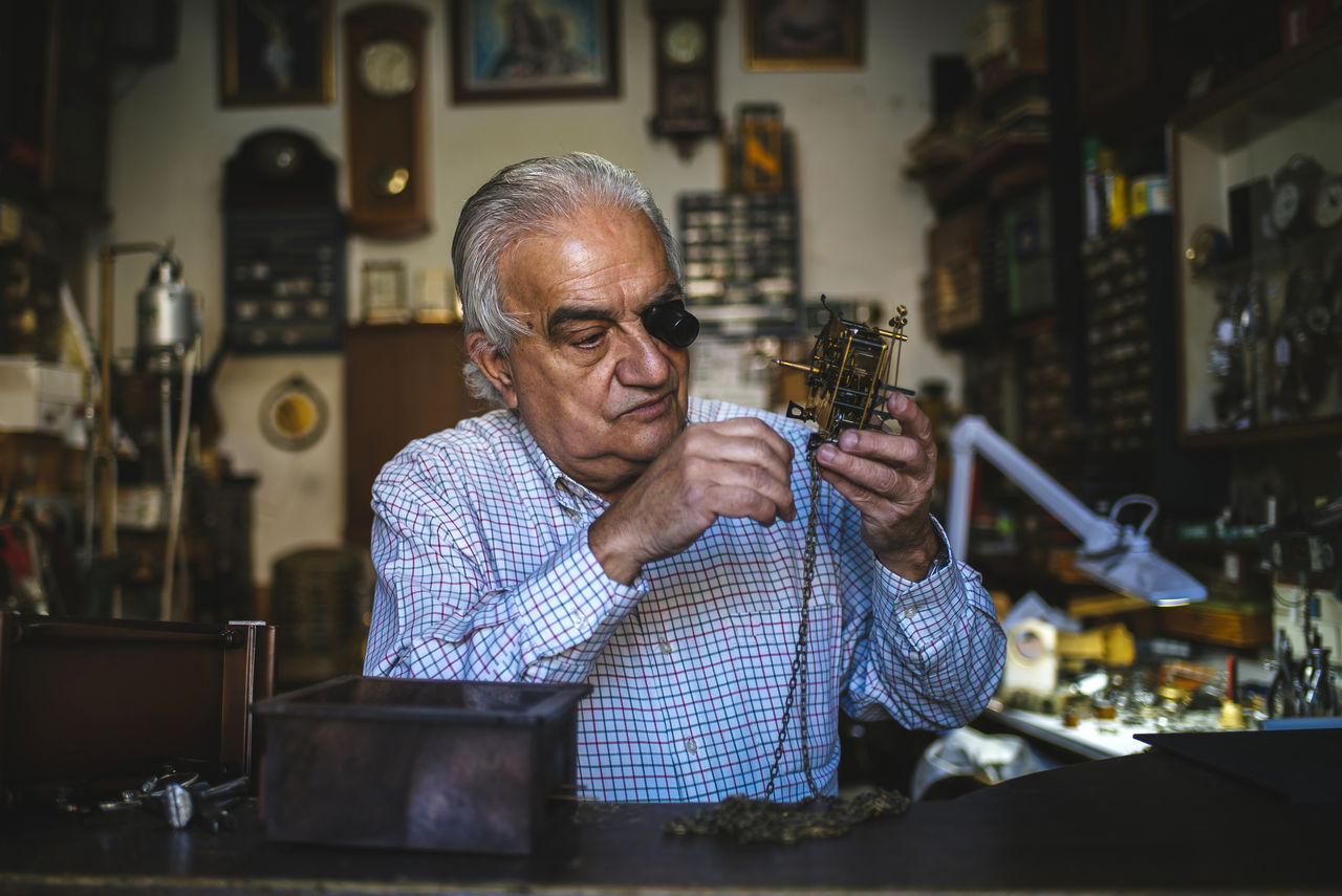 Watchmaker with okular working with an old watch