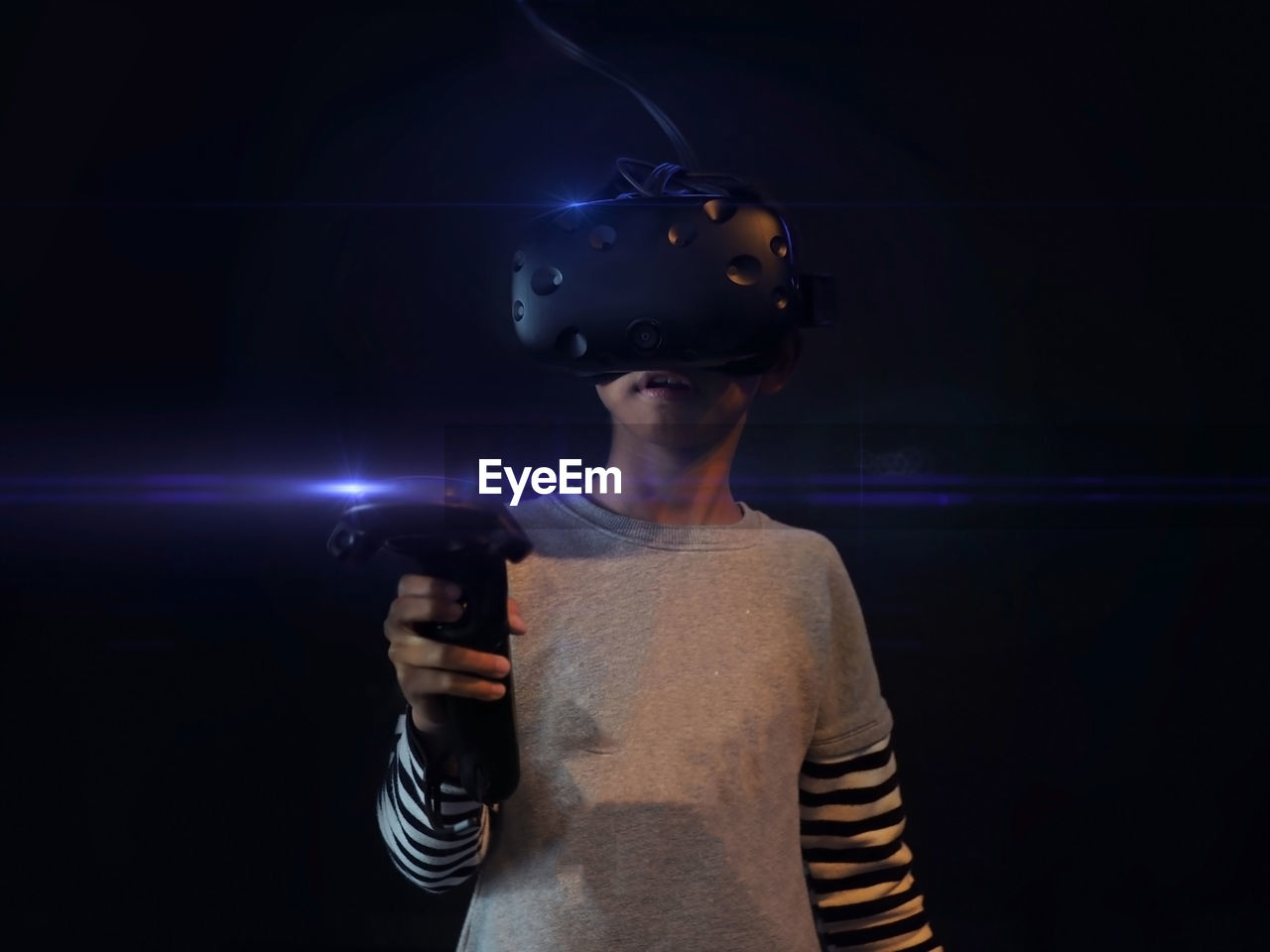 Young asian boy holding and wearing vr game set in the black background. selected focus.