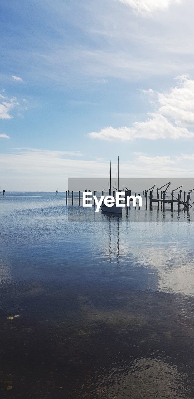 WOODEN POSTS ON SEA AGAINST SKY