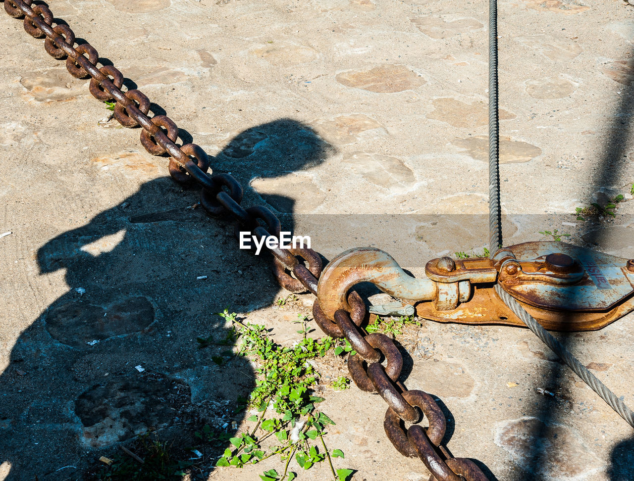 HIGH ANGLE VIEW OF CHAIN TIED TO METAL WALL