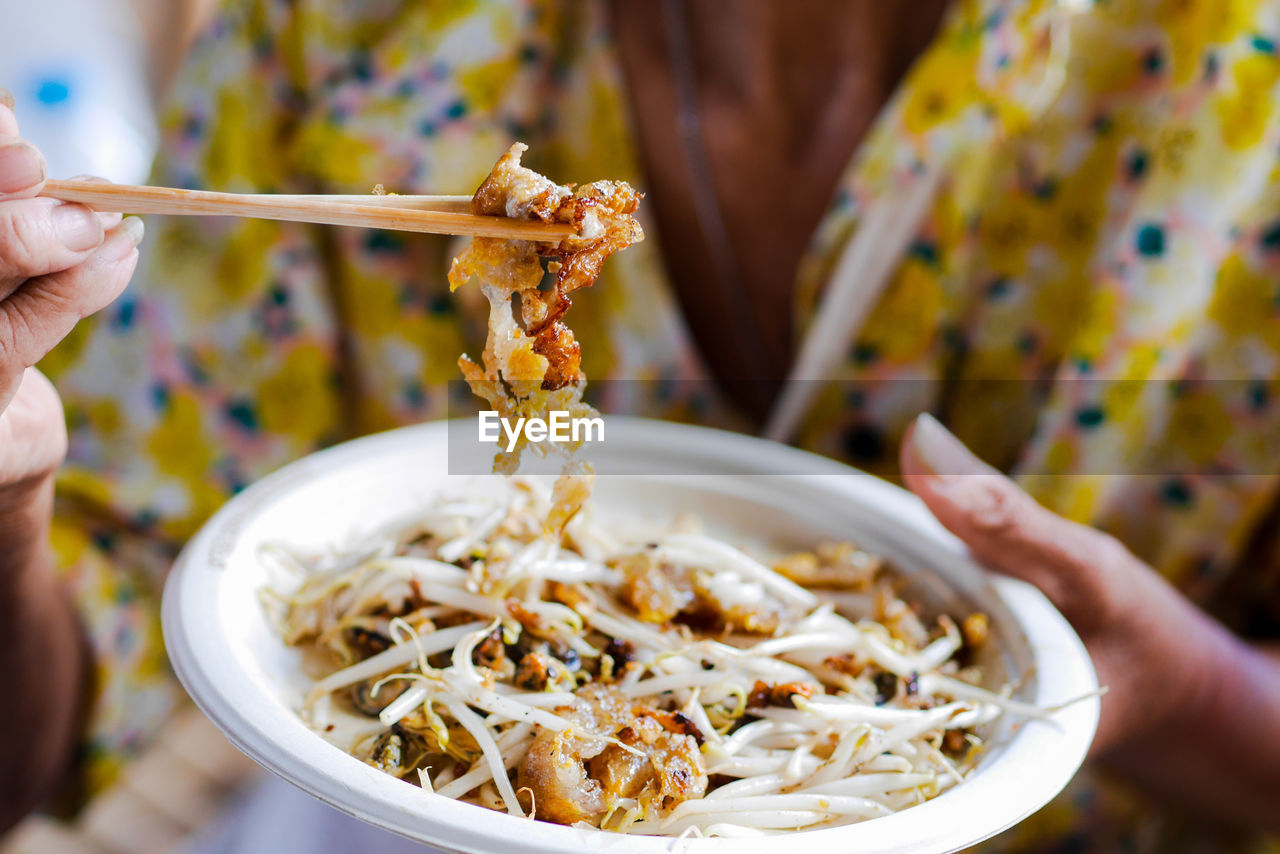 Close-up of hand holding noodles in bowl