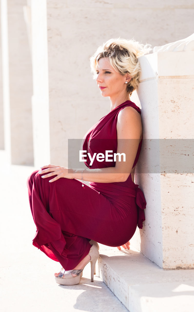 Mid adult woman looking away while leaning on wall