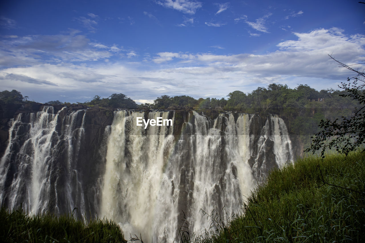 scenic view of waterfall in forest against sky