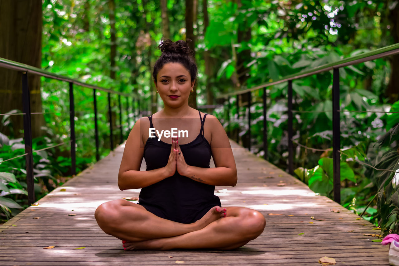 Portrait of woman practicing yoga on footbridge