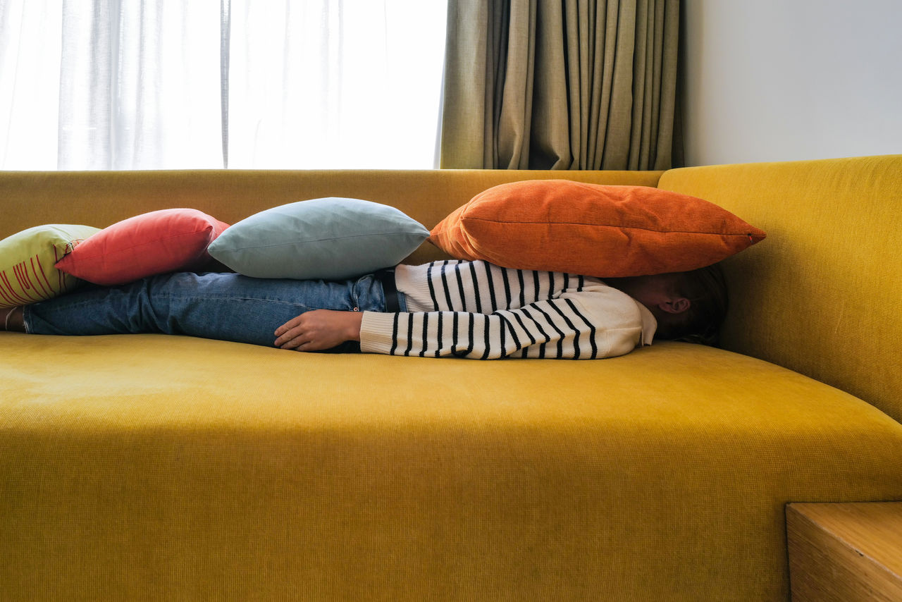 Woman relaxing on the sofa with colorful pillows on top of her body