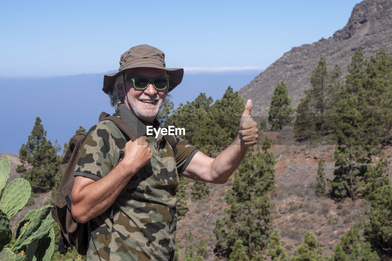 Portrait of smiling young man wearing sunglasses against sky