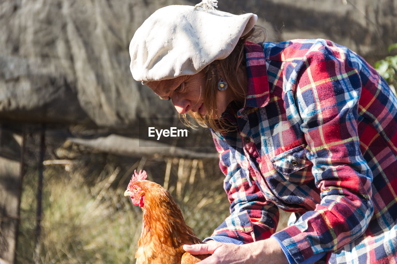 Mature woman with hen at farm