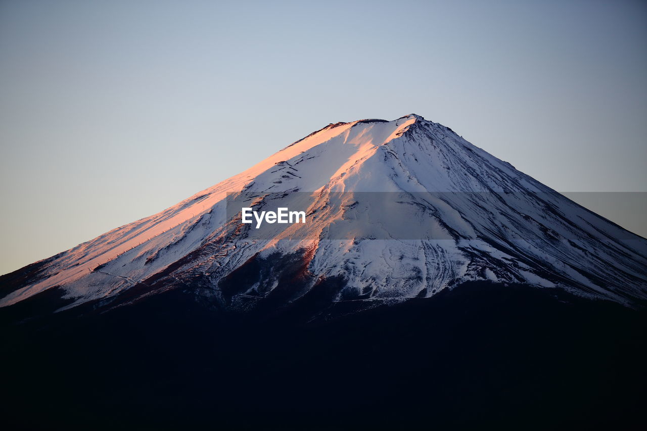 Low angle view of snowcapped mountain against clear sky