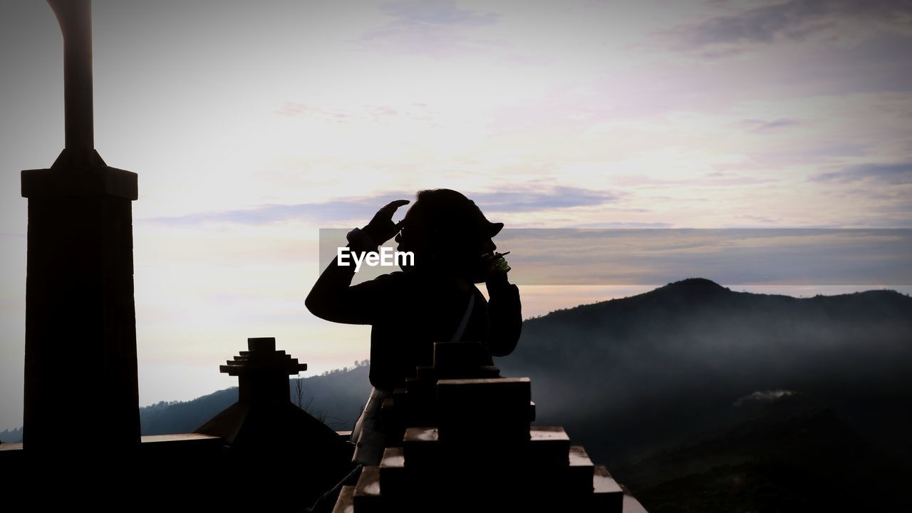 Silhouette man photographing against sky during sunset