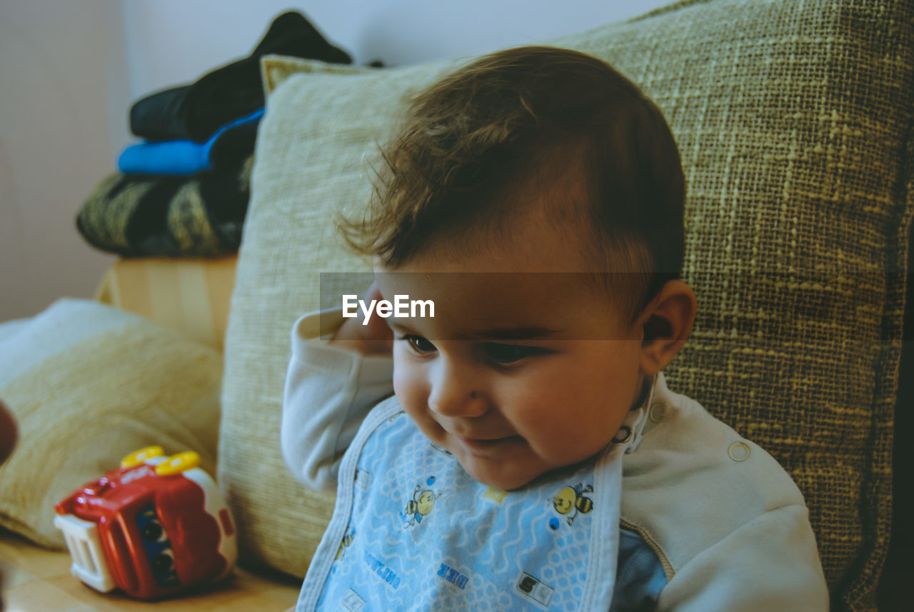 Close-up of cute boy sitting on bed at home