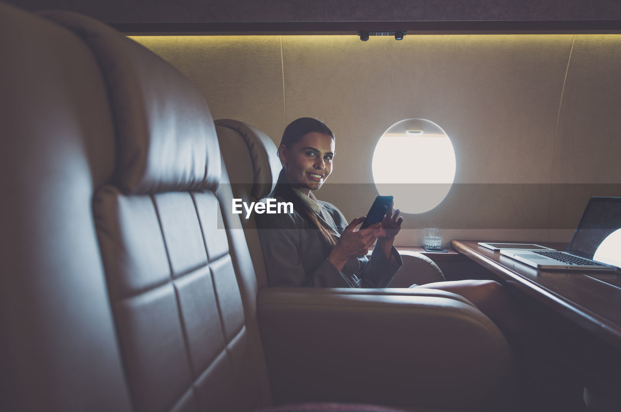 Smiling businesswoman using laptop in airplane