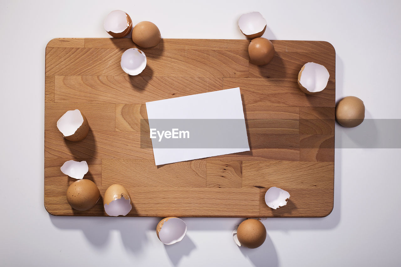 Directly above shot of paper and broken eggshells on cutting board