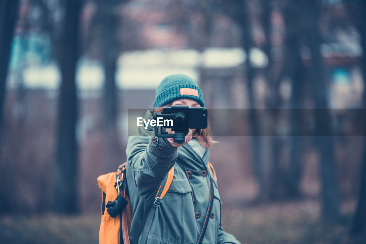 Mid adult woman photographing while standing in forest