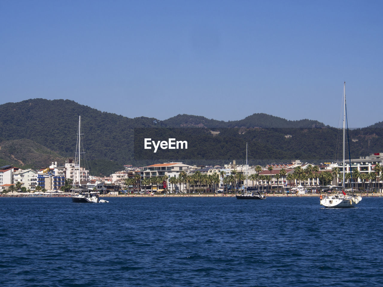 Yachts sailing on aegean sea against clear blue sky