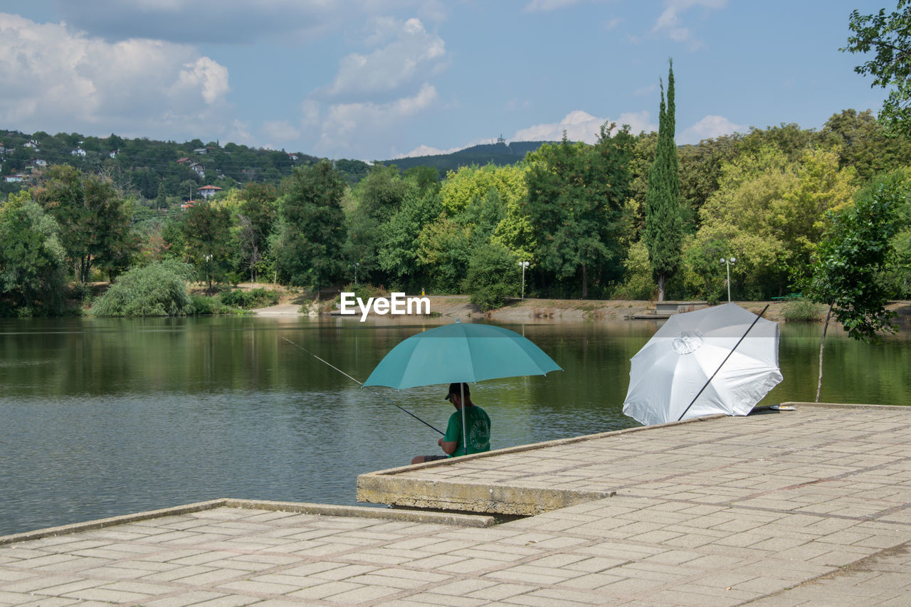 REAR VIEW OF MAN ON LAKE AGAINST SKY