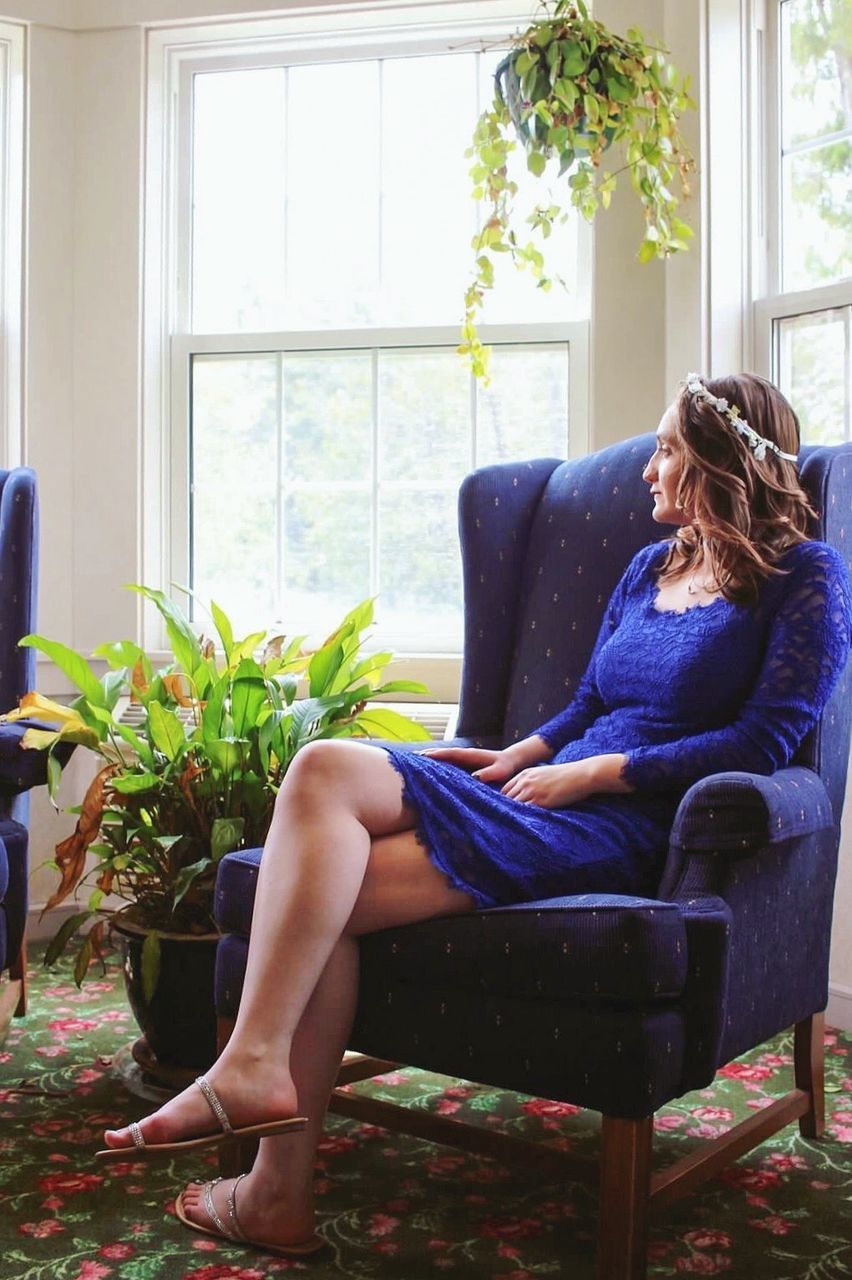 Beautiful woman sitting on chair by window at home