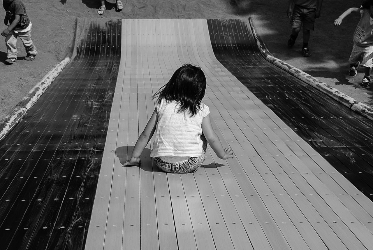 Rear view of girl playing on slide during sunny day