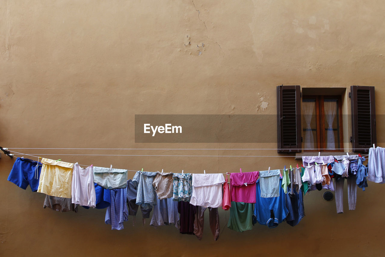 Clothes drying on clothesline by beige wall