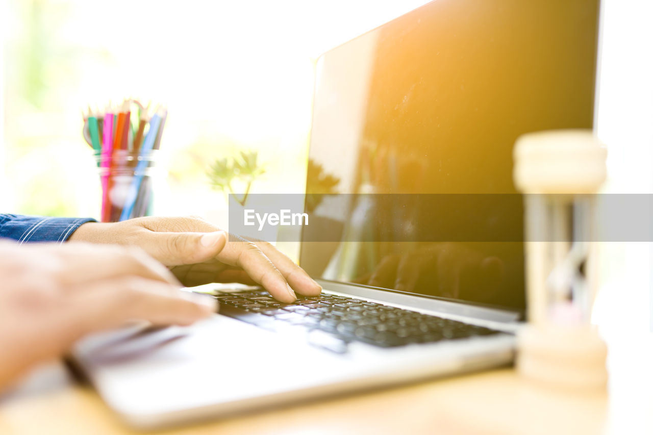 Cropped hands of man using laptop on table