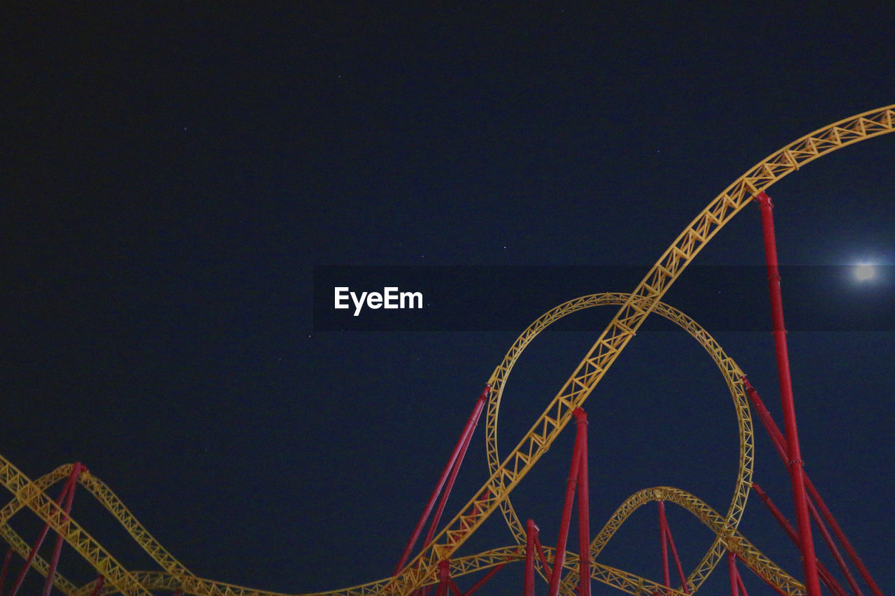 Low angle view of rollercoaster against sky at night