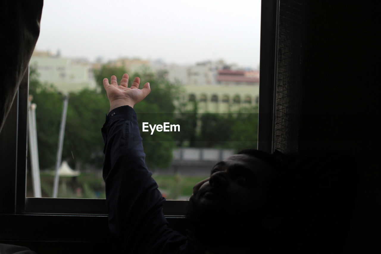 Man reaching hand on window at home