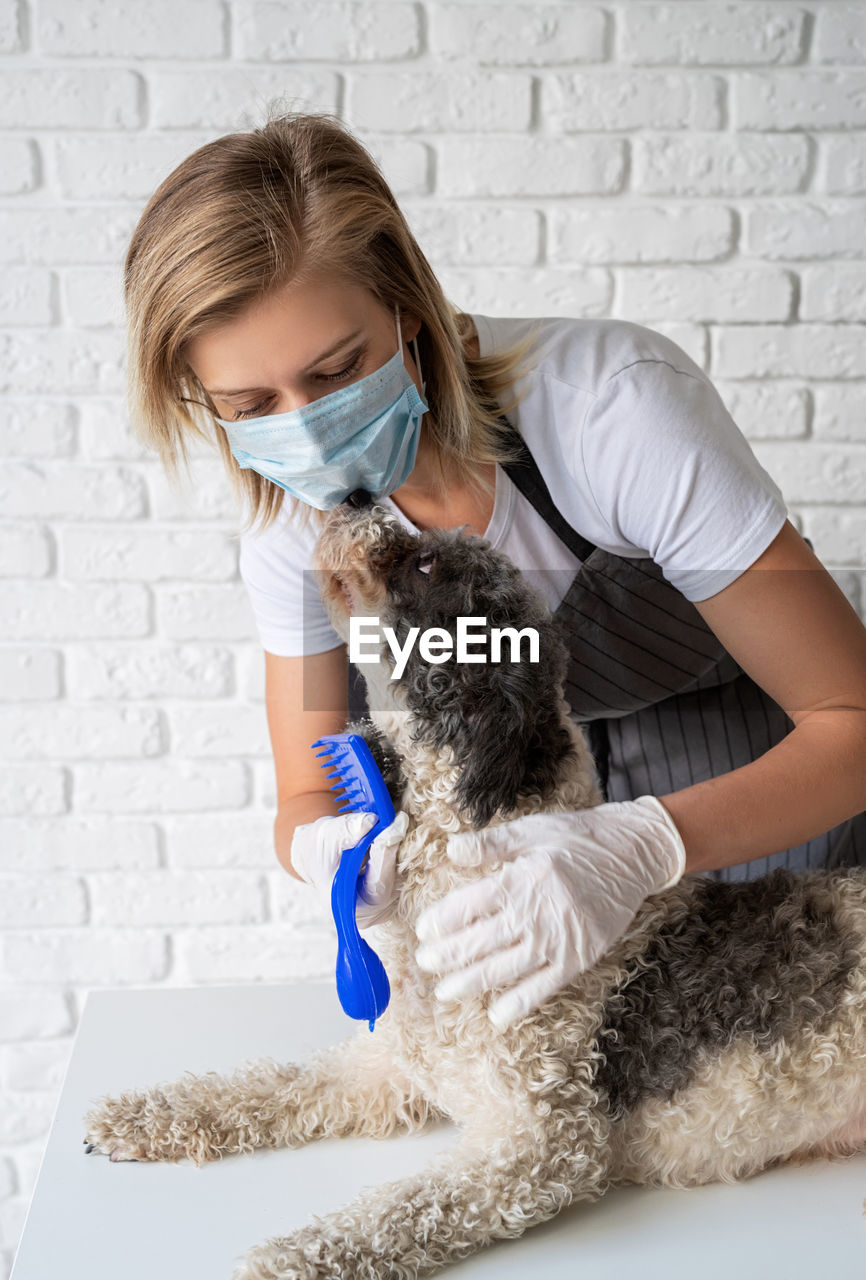 Young woman with dog sitting against wall at home