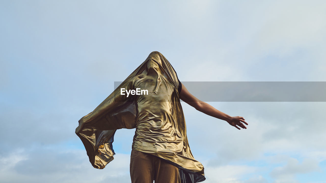 Low angle view of man covered with fabric against sky