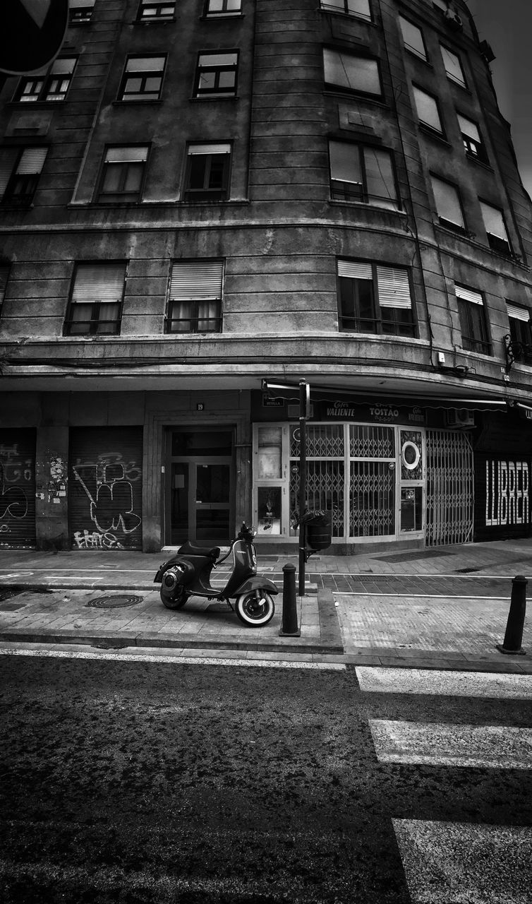 Scooter parked on sidewalk by road against building