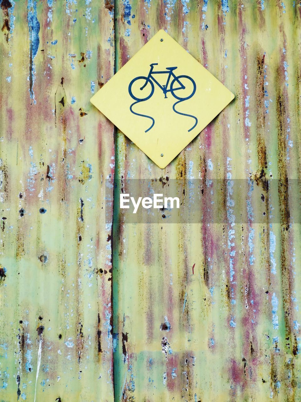 Bicycle sign on damaged corrugated iron