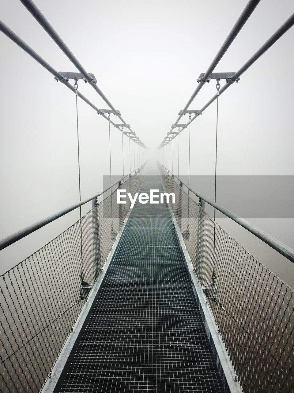 Empty footbridge leading towards sky