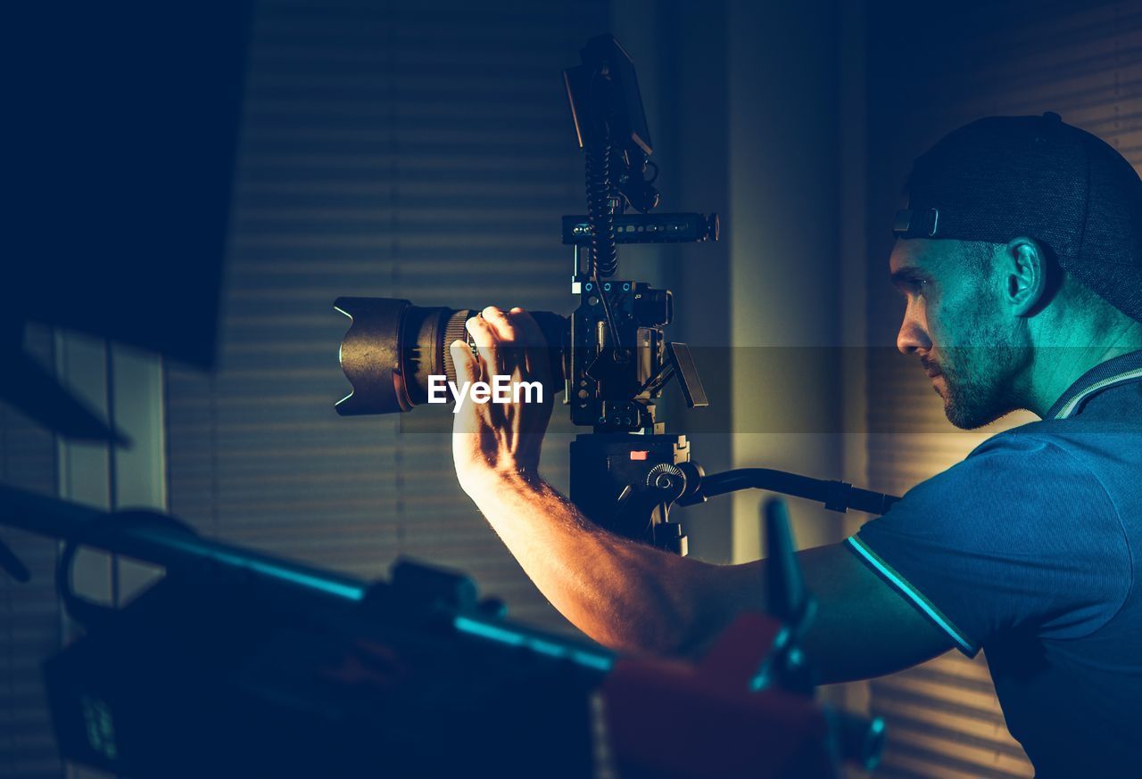 Side view of man adjusting camera