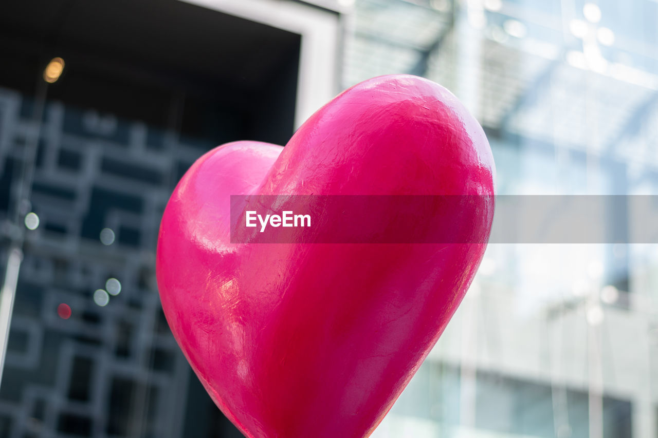 CLOSE-UP OF HEART SHAPE WITH PINK BALLOON AGAINST BUILT STRUCTURE