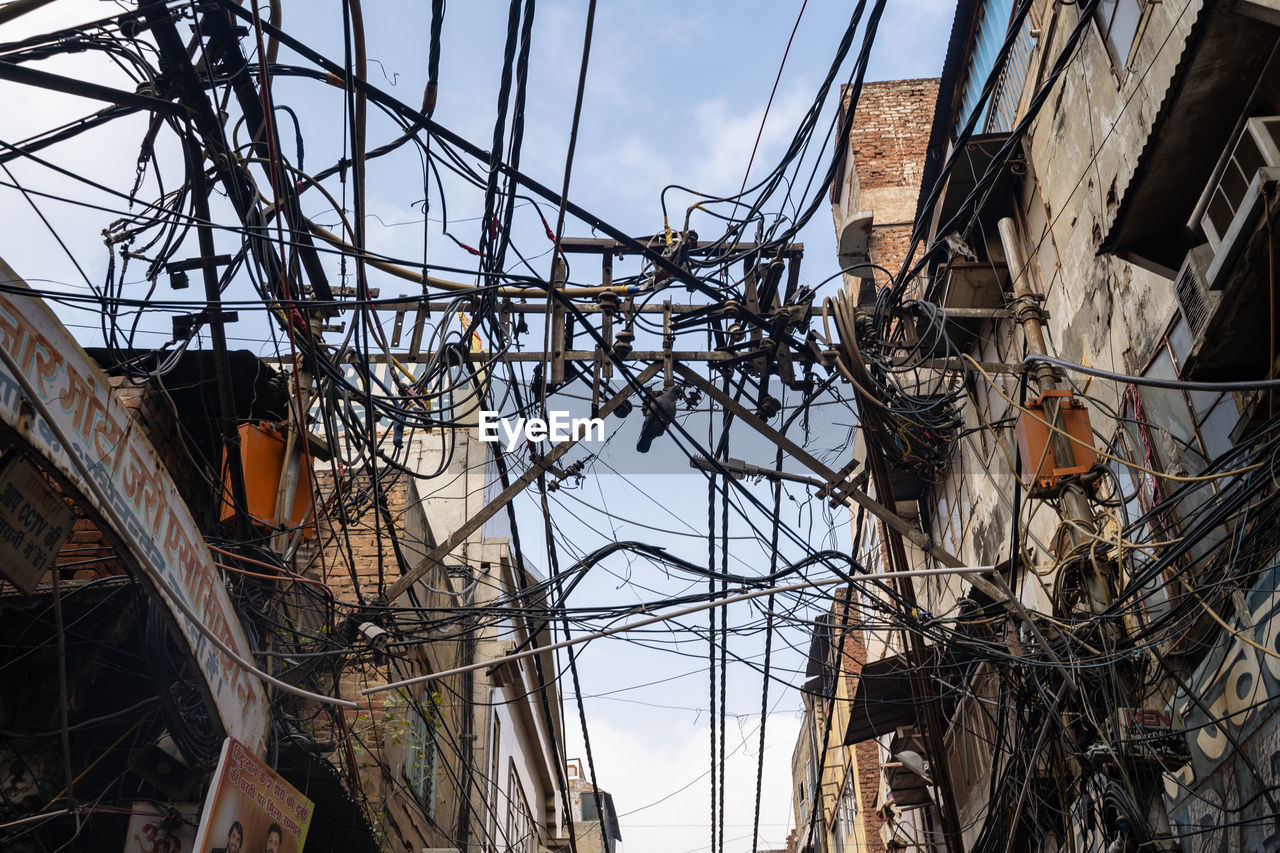 Low angle view of electricity pylon and buildings against sky