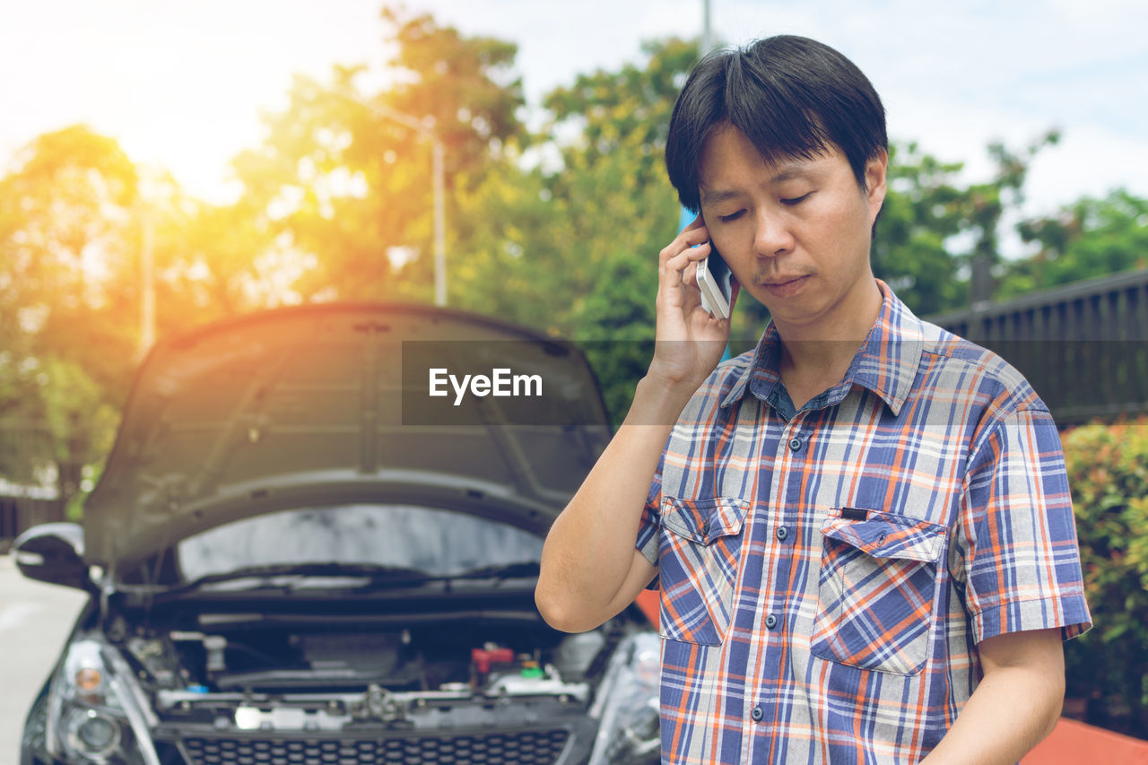 Man talking on mobile phone by car