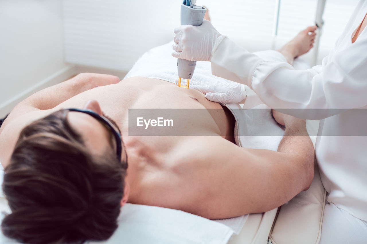 Shirtless man receiving electrolysis treatment