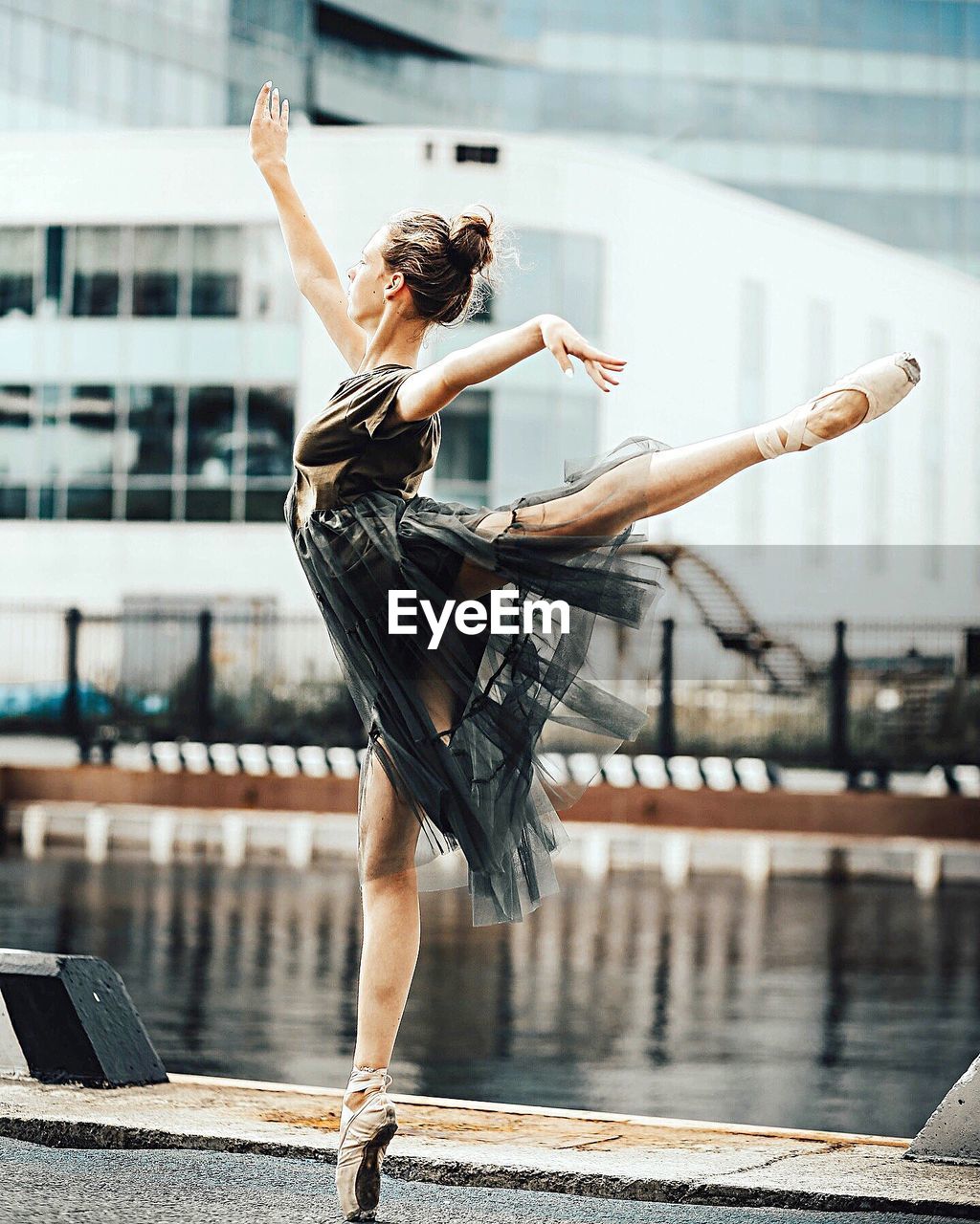 YOUNG WOMAN JUMPING ON POLE IN CITY DURING WINTER