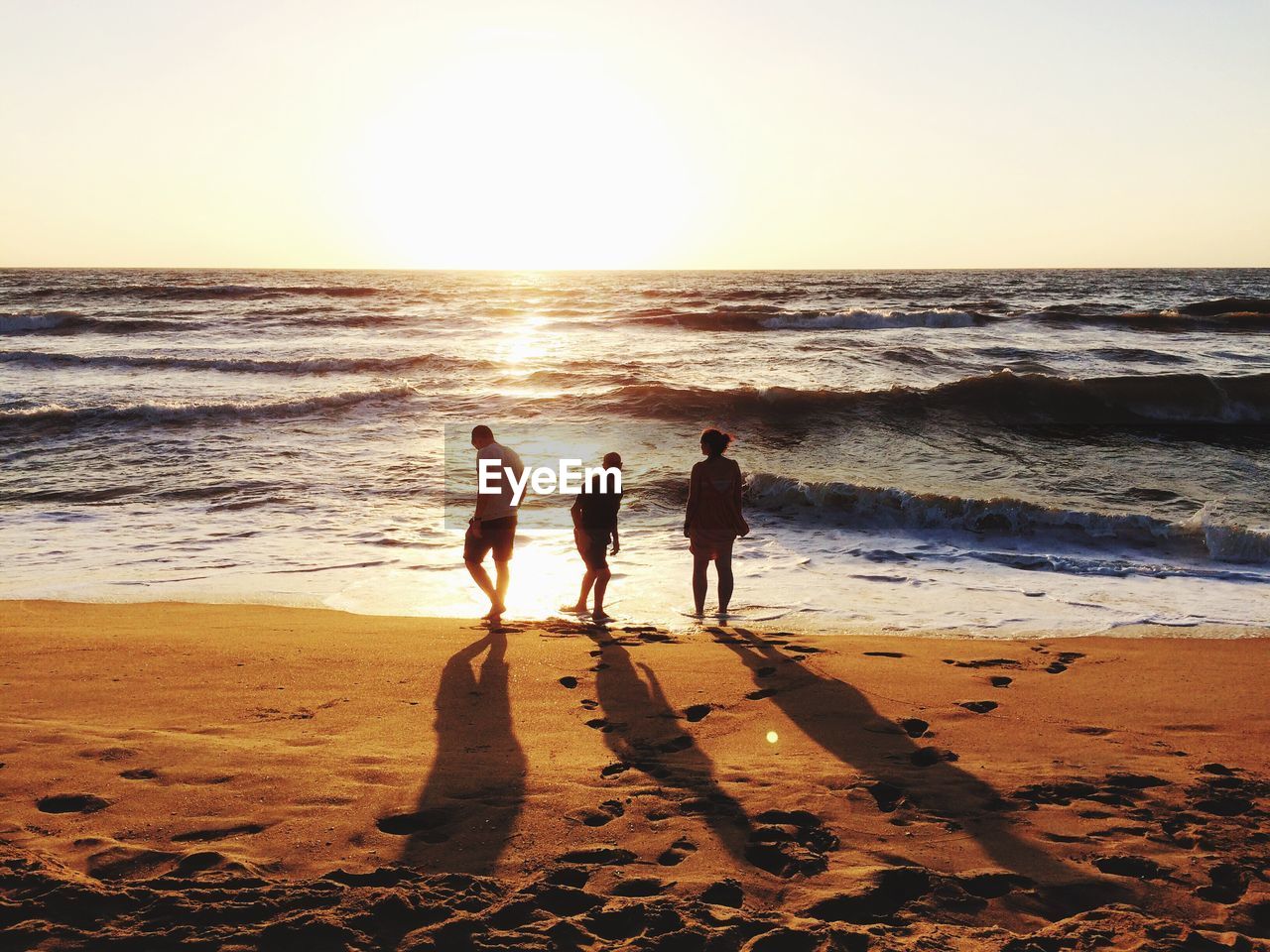 People on beach against sky during sunset