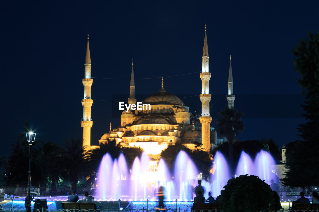 Water fountain against illuminated sultan ahmed mosque at night