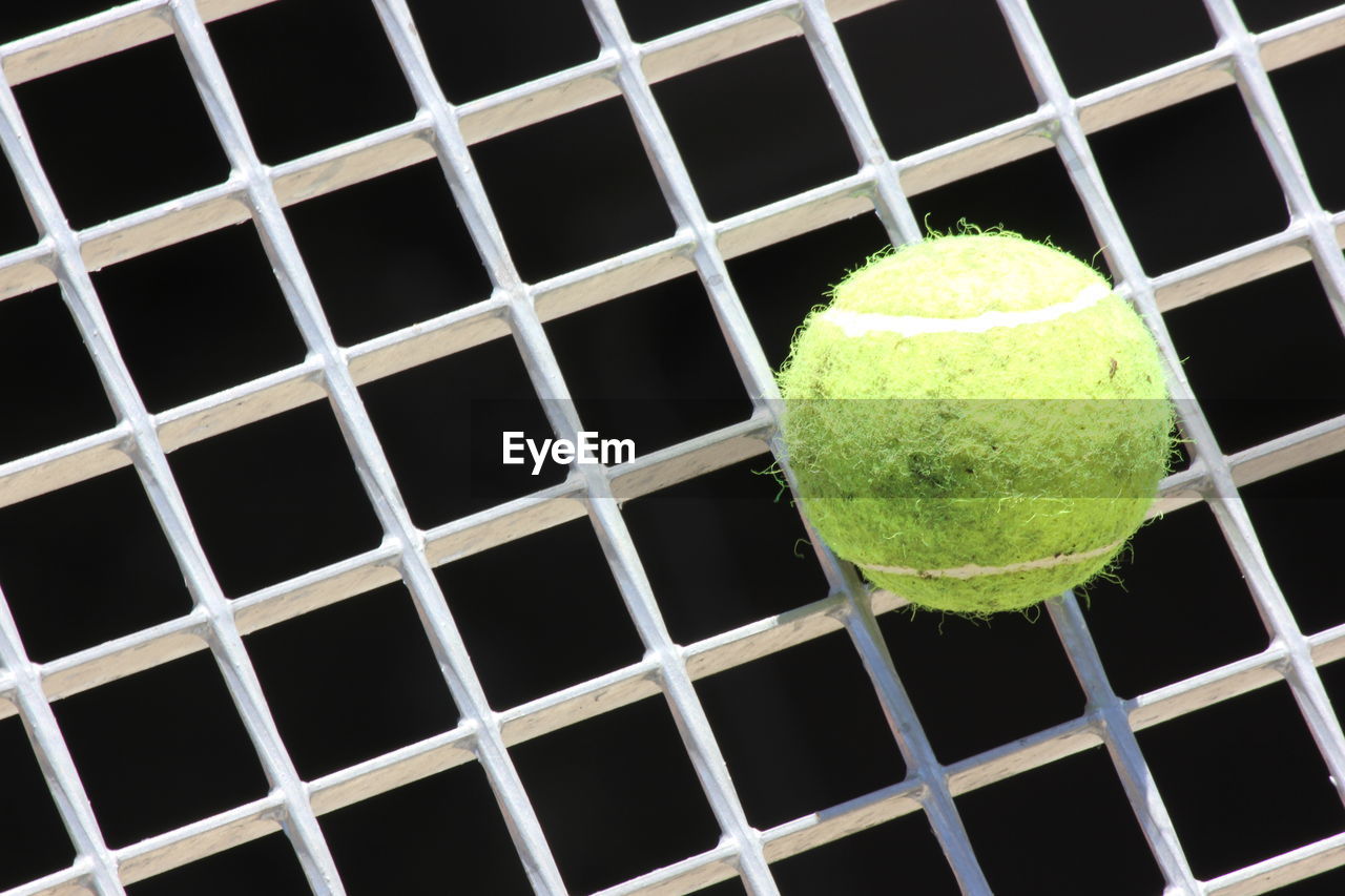 Close-up of tennis ball on metal grate