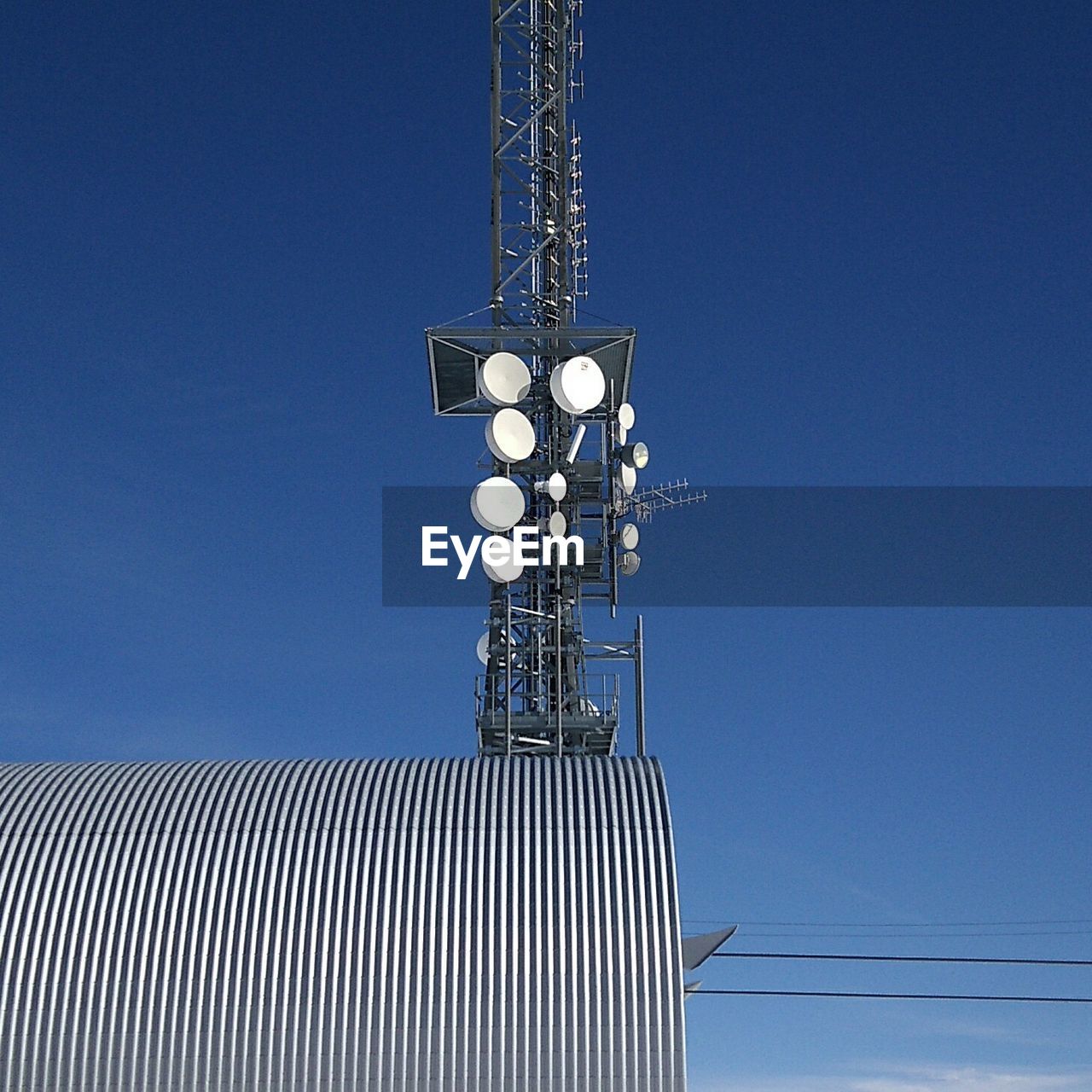 Low angle view of communications tower against clear blue sky