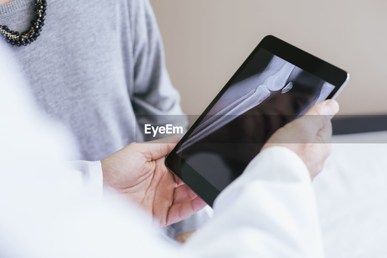 Close-up of doctor explaining x-ray image to patient on tablet computer